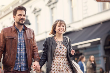 Cute urban couple holding hands, walking down the sunset street in summer, having fun together