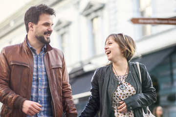 Cute urban couple holding hands, walking down the sunset street in summer, having fun together
