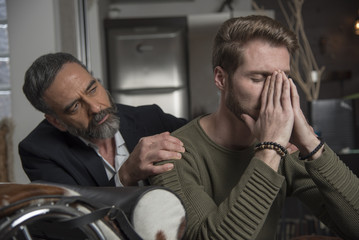 Elderly professional psychotherapist, shrink, comforting his depressed young patient who is feeling anxious and depressed