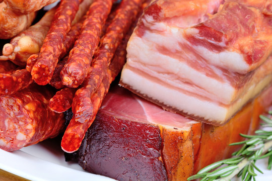 Smoked sausages with bacon and prosciutto crudo in a plate on table
