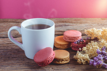Different types color of macaroons with Cup of hot tea on Old grunge wooden background