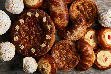Homemade Russian Easter baked goods, kulichi, patties with cottage cheese, karavai and loaf cake with nuts on festive table background