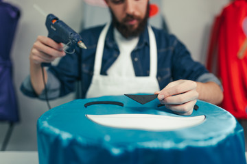 Young man working in the craft shop, using the silicone gun