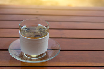 hot tea in glass on wood table and sunlight in this morning.