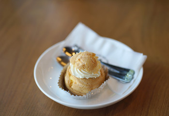 Choux cream on the white plate with fork and spoon
