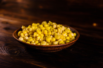 Ceramic plate with canned corn seeds on wooden table