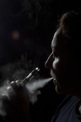 Fototapeta na wymiar Silhouette of a woman with an electronic cigarette