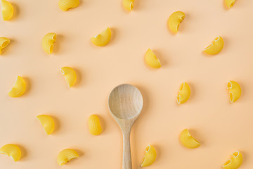 Top view of pipe rigate pasta pattern and wooden spoon on colorful pastel background