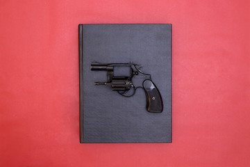 Book and gun on red background