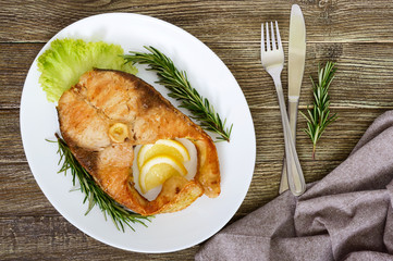 Big roasted carp steak with lemon and rosemary. Top view.