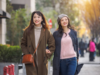 Cute positive portrait of best friend pretty young girls, natural glowing makeup, Two young hipster girl sisters walking hand in hand together in sunny street and having fun together.