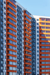 A multi-storey residential building painted in different colors against the blue sky, a freshly constructed one is waiting for new tenants to enter it
