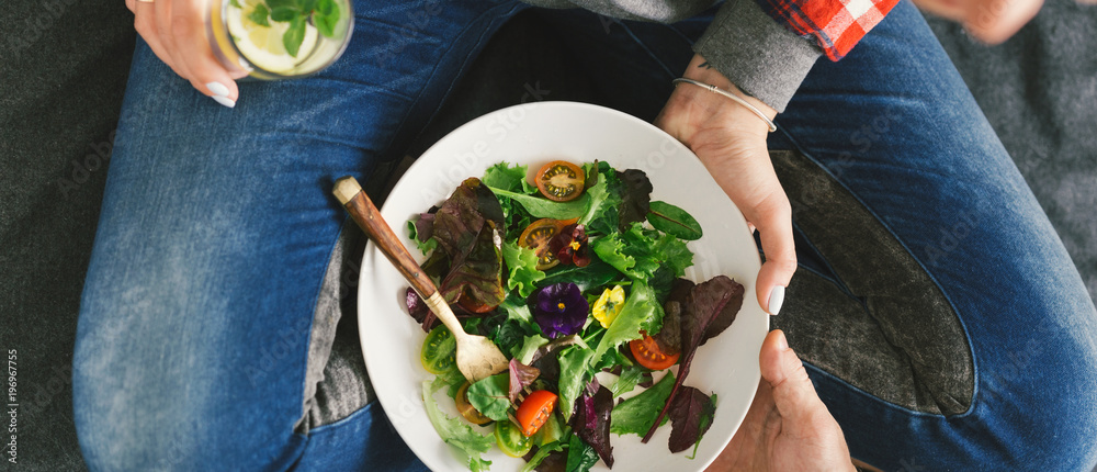 Wall mural close up woman eating salad top view healthy food