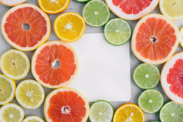 Fototapeta na wymiar Top view paper sheet with sliced citrus fruit on light background. Flat lay. Summer background