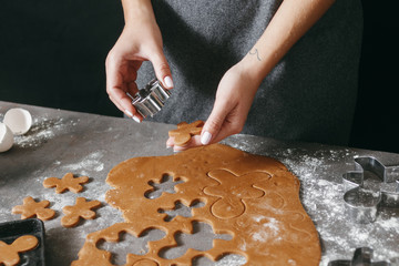 Woman cooking festive Christmas gingerbread cookies in the home kitchen