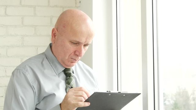 Businessman Working in Office Room Check and Fill Documents from a Clipboard
