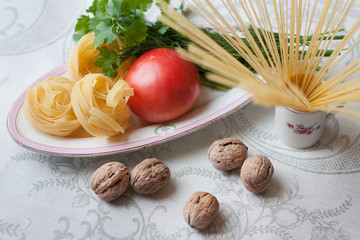kitchen still life of vegetables, nuts, fettuccine and parsley on the table