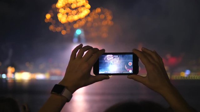 Hands Taking Pictures Of Firework With Mobile Phone