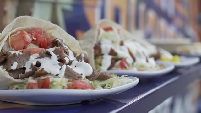 Close up shot of a row of prepared gyro sandwiches on plates at a food truck
