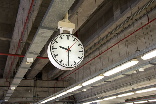 clock is hanging on the steel arch roof structure at train station,