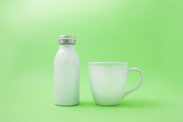 White cup with a white thermo bottle on a green background