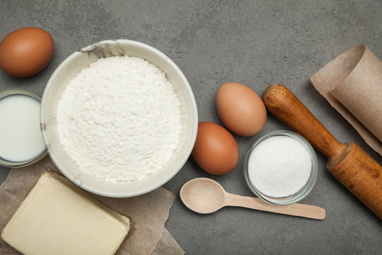 Gray concrete, sugar, eggs, flour and butter on a white background.