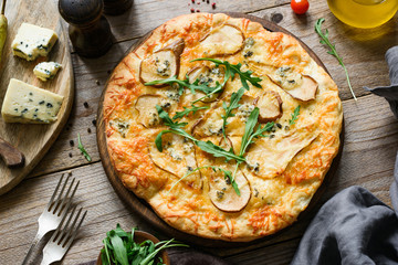 Quatro formaggi pizza with pear. Pear and blue cheese pizza on wooden board garnished with arugula,...
