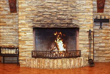 Fototapety  Burning fireplace and fireplace accessories in a large room
