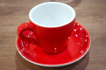 Close-up of a red empty cup and saucer on a wooden table