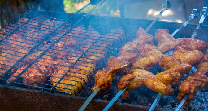 Photo of delicious chicken wings barbecue fried on charcoal in the park