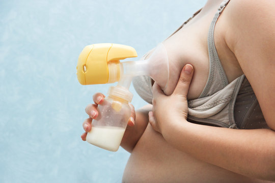 Young mother pumped breast milk. pump works on batteries, convenient to use. Breast milk for supplementary feeding, infant nutrition. feeding bra with detachable valves. Breast Pump in Female Hand