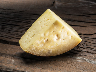 Piece of homemade cheese on the wooden background.