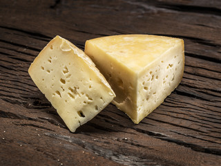 Pieces of homemade cheese on the wooden background.