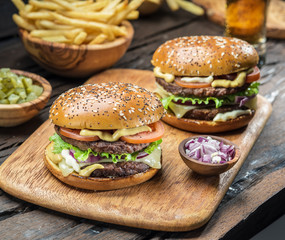 Hamburgers and French fries on the wooden tray.