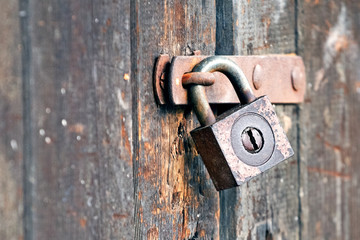 Old rusty padlock on wooden gate