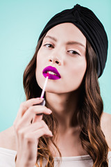 Woman applying lipstick. Beautiful girl makes makeup. Fashion, purple color, fashion portrait.