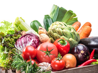Fresh multi-colored vegetables in wooden crate.