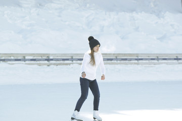 Teen girl skating on outdoor public ice rink