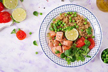 Healthy dinner. Slices of grilled salmon, quinoa, green peas, tomato, lime and lettuce leaves. Flat lay. Top view