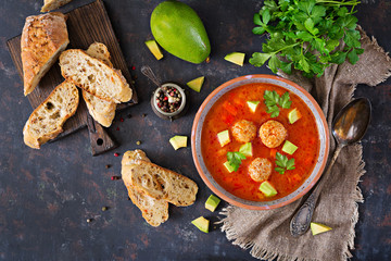 Spicy tomato soup with meatballs and vegetables. Served with avocado and parsley. Healthy dinner.Flat lay. Top view