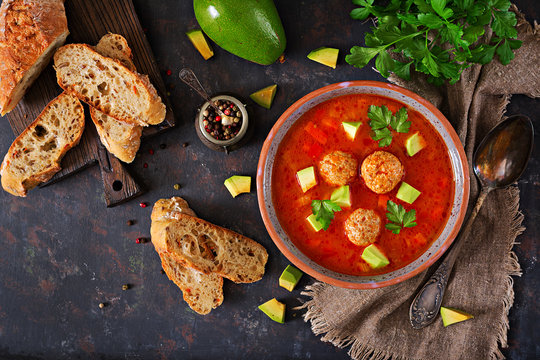 Spicy tomato soup with meatballs and vegetables. Served with avocado and parsley. Healthy dinner.Flat lay. Top view