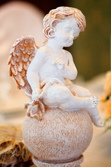 The figurine of a little angel among the decorations on the occasion or holiday.