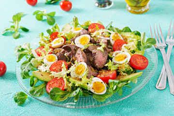Warm salad from chicken liver, avocado, tomato and quail eggs. Healthy dinner. Dietary menu.