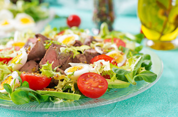 Warm salad from chicken liver, avocado, tomato and quail eggs. Healthy dinner. Dietary menu.