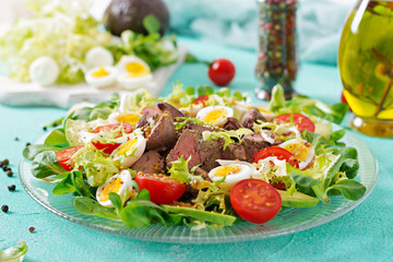 Warm salad from chicken liver, avocado, tomato and quail eggs. Healthy dinner. Dietary menu.