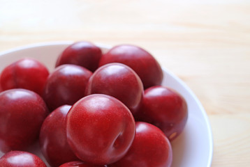 Ripe Gulf Ruby Plum Fruits Piled up on White Plate Served on Wooden Table 