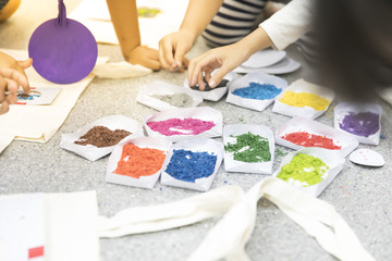 Close up hands of a kids drawing on paper with many color