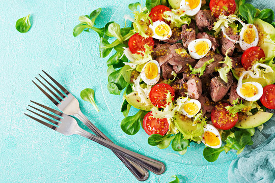 Warm salad from chicken liver, avocado, tomato and quail eggs. Healthy dinner. Dietary menu. Flat lay. Top view