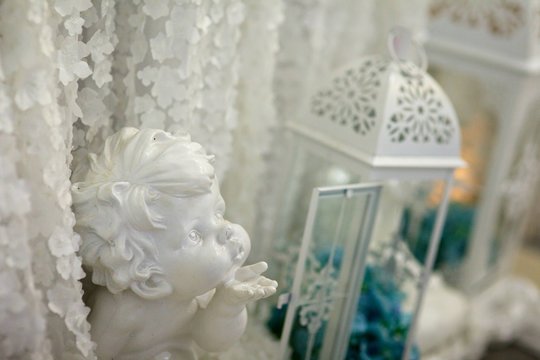 The figurine of a little angel among the decorations on the occasion or holiday.