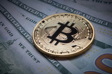 Close-up of gold bitcoin and dollars